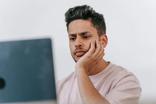Frowning ethnic man working on laptop