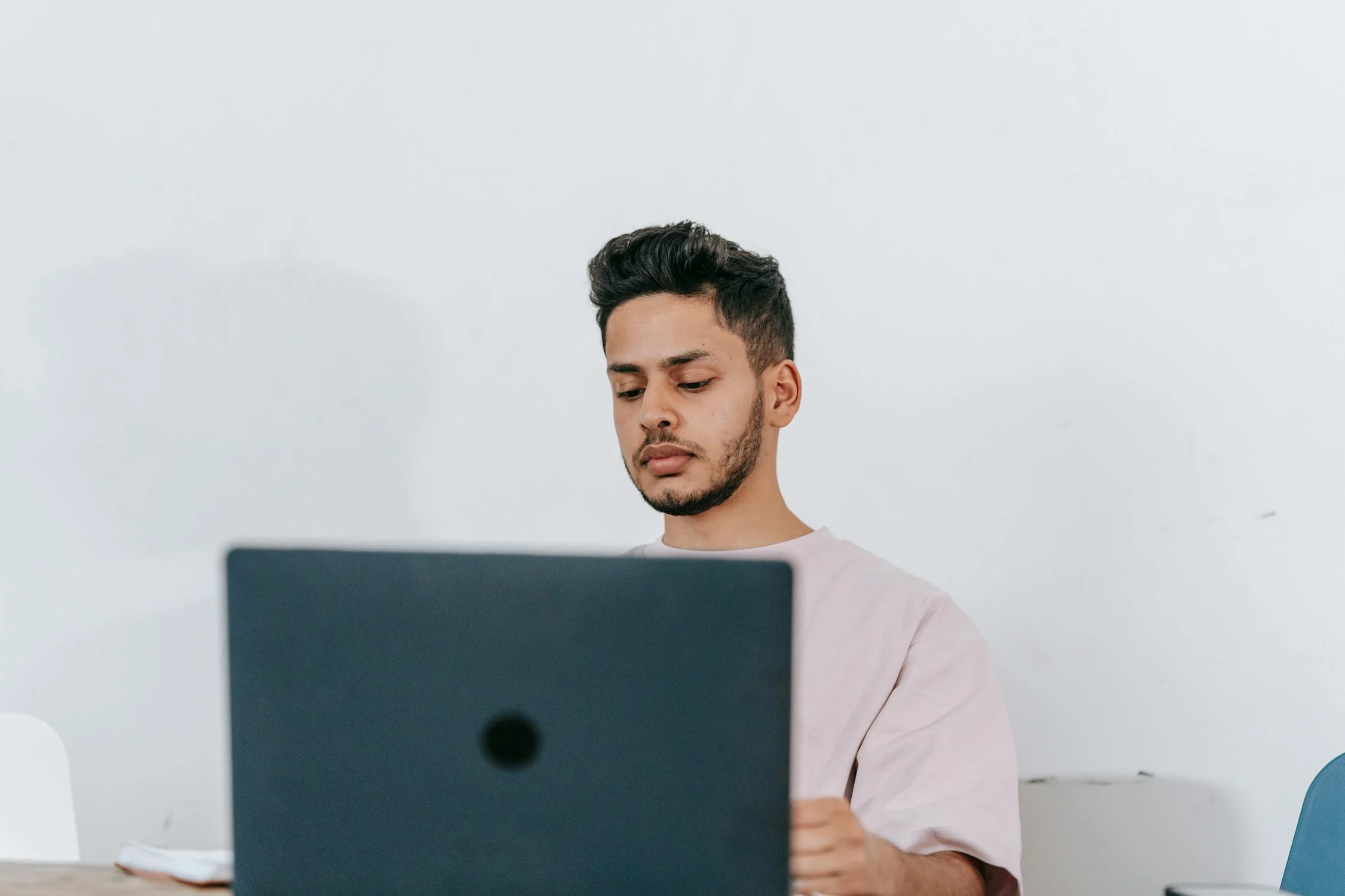 Thoughtful ethnic man working on laptop in light room